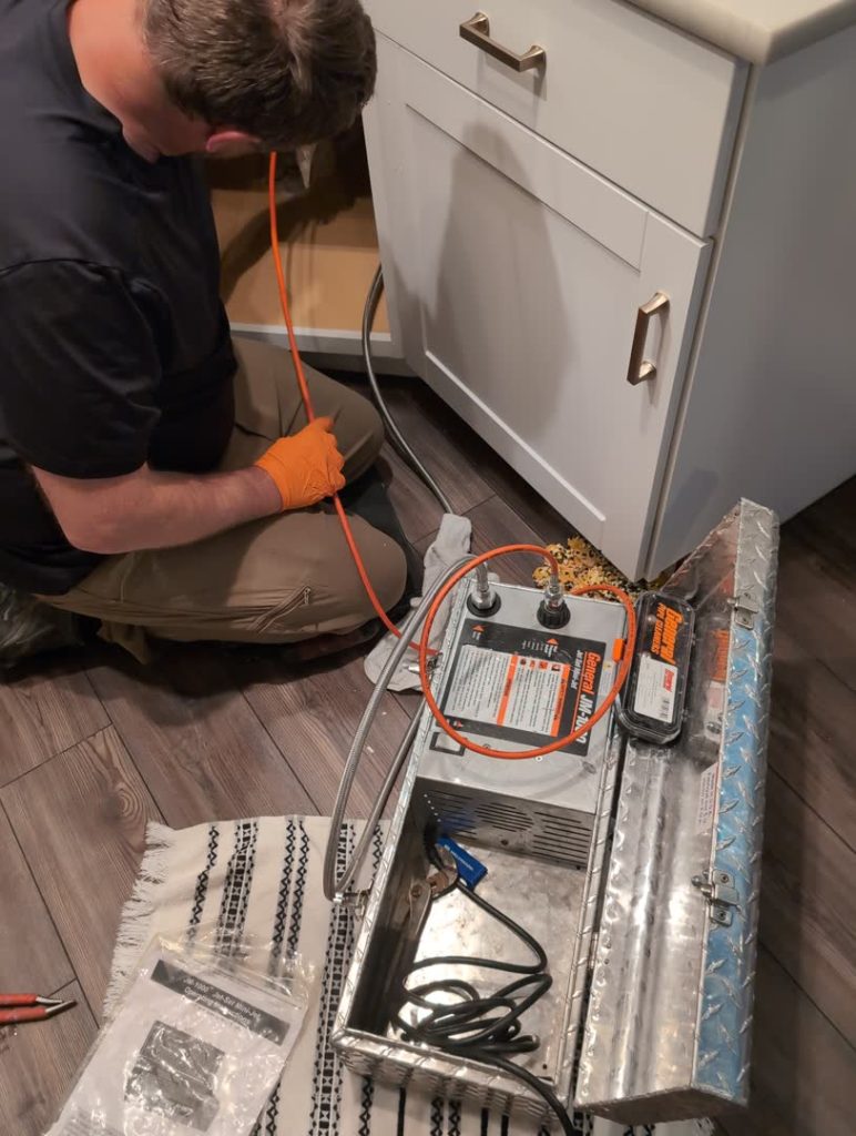 Plumber using a drain cleaning sewer jetter in a bathroom